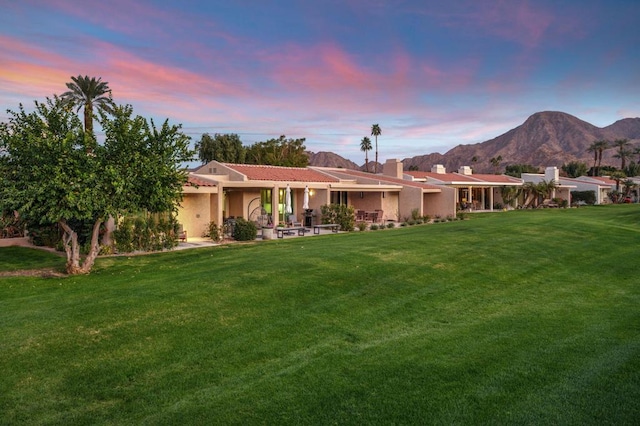 view of front of property with a mountain view and a lawn