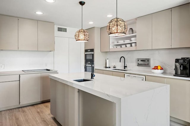 kitchen with an island with sink, sink, and pendant lighting