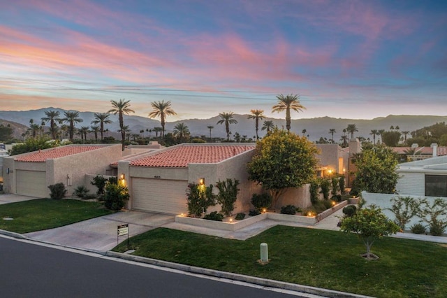 view of front of property with a garage, a mountain view, and a lawn