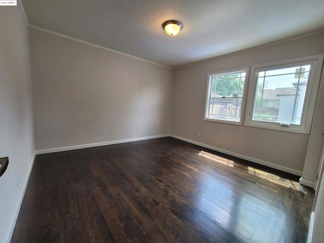 empty room with ornamental molding, dark hardwood / wood-style floors, and a textured ceiling