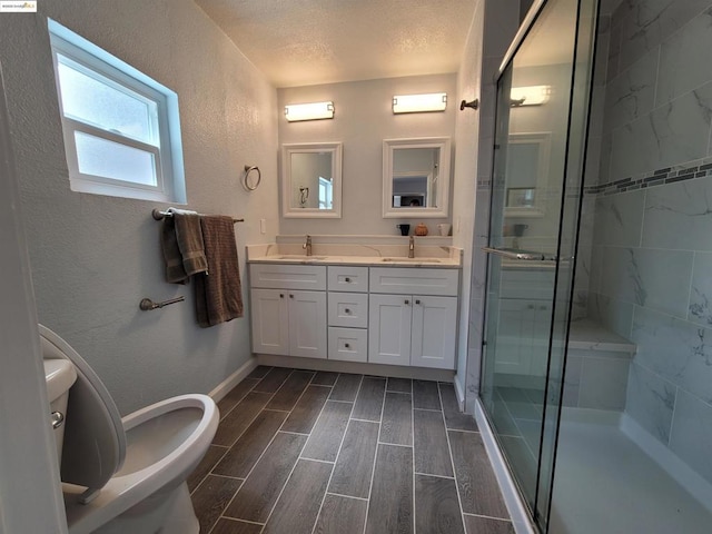 bathroom featuring a bidet, a shower with door, vanity, a textured ceiling, and toilet