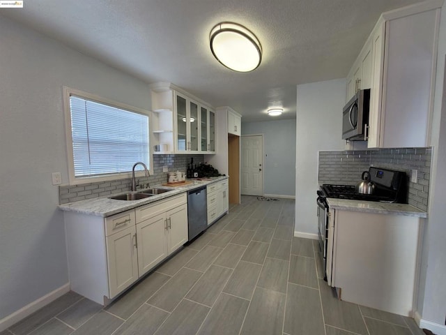 kitchen featuring sink, appliances with stainless steel finishes, light stone counters, tasteful backsplash, and white cabinets