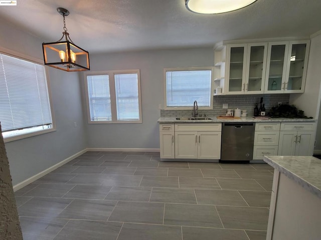 kitchen with white cabinetry, sink, hanging light fixtures, stainless steel dishwasher, and light stone counters