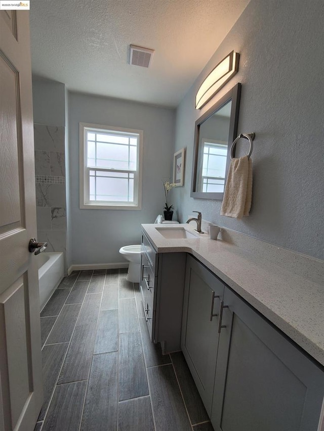 full bathroom featuring vanity, a wealth of natural light, a textured ceiling, and toilet