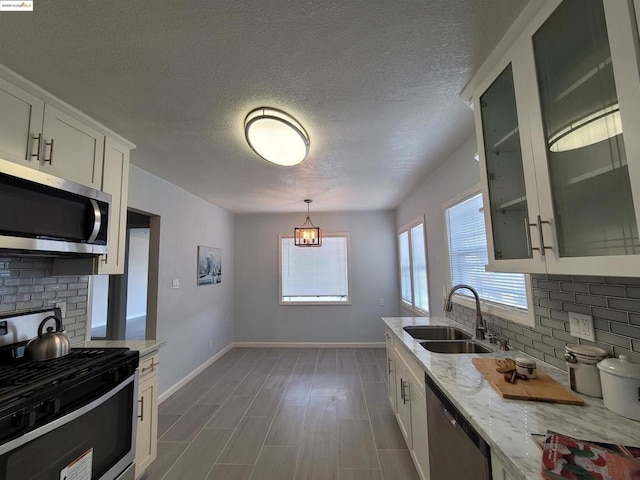 kitchen featuring stainless steel appliances, light stone countertops, sink, and white cabinets