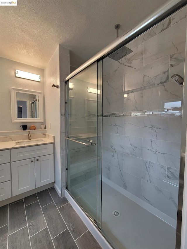 bathroom with an enclosed shower, vanity, and a textured ceiling