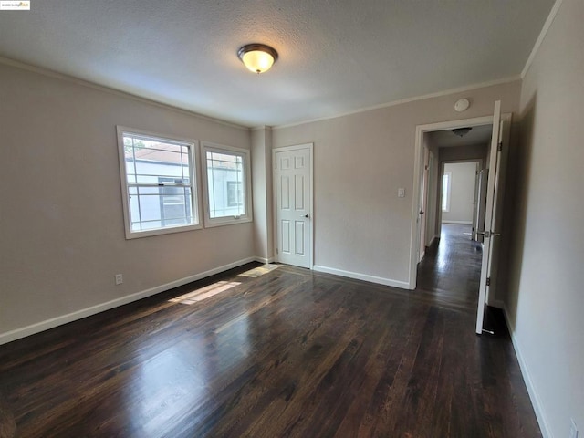 empty room with ornamental molding, dark hardwood / wood-style floors, and a textured ceiling