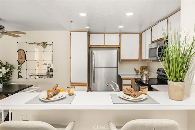 kitchen featuring a kitchen bar, kitchen peninsula, white cabinets, and appliances with stainless steel finishes