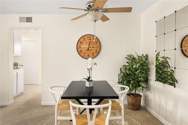 dining space featuring light carpet and ceiling fan