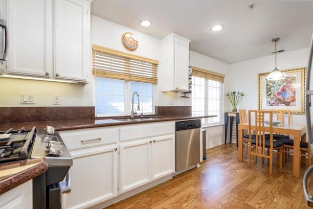 kitchen featuring sink, hanging light fixtures, light wood-type flooring, stainless steel appliances, and white cabinets