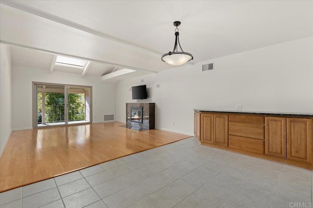 unfurnished living room with vaulted ceiling with beams, a multi sided fireplace, and light tile patterned floors