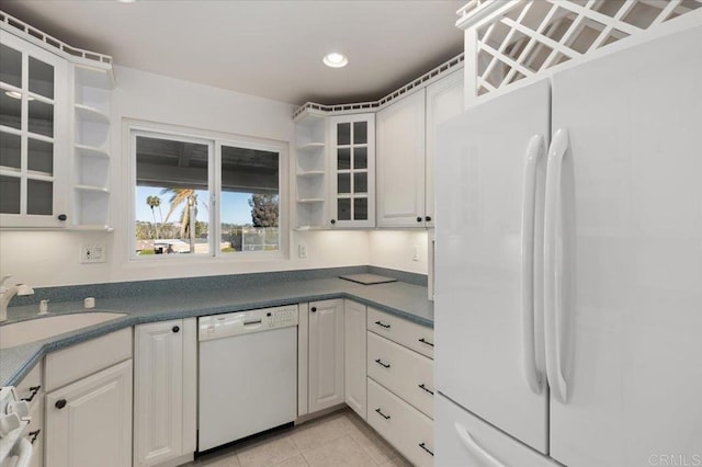 kitchen featuring sink, white appliances, light tile patterned floors, and white cabinets