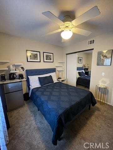 bedroom with ceiling fan, dark carpet, and a closet