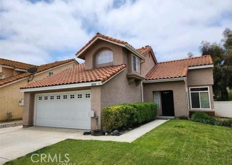 mediterranean / spanish-style house with a garage and a front lawn