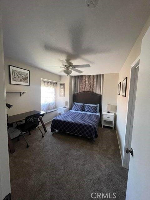 carpeted bedroom with ceiling fan and a textured ceiling