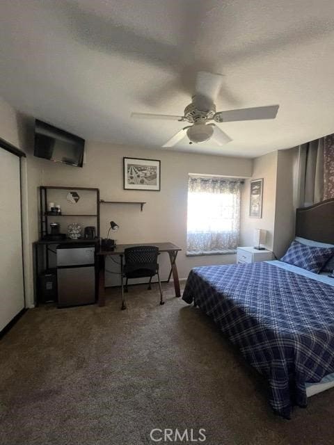 carpeted bedroom featuring ceiling fan and refrigerator