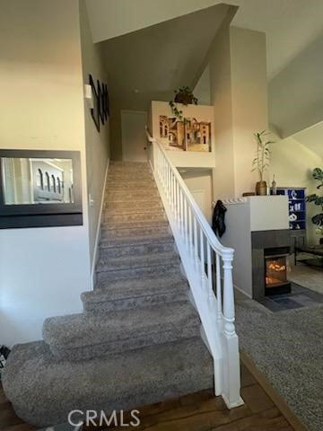 staircase with a high ceiling and a multi sided fireplace