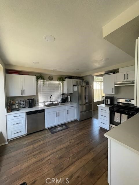 kitchen with sink, dark wood-type flooring, stainless steel appliances, and white cabinets