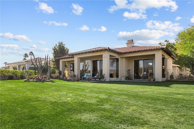 rear view of house with a tiled roof, a yard, a chimney, and a patio