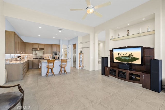 living area featuring arched walkways, a ceiling fan, and recessed lighting