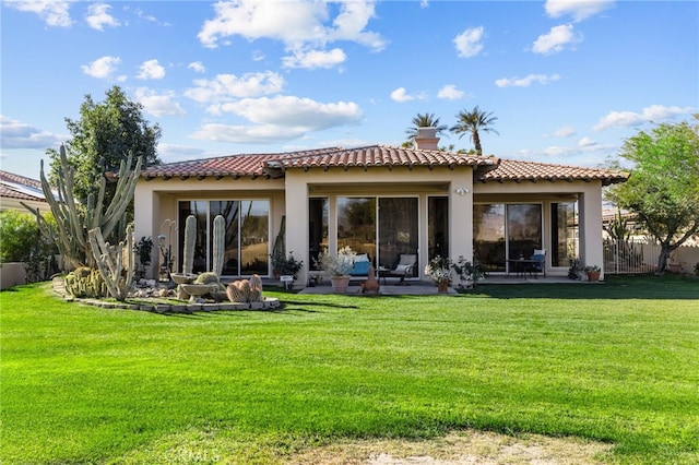 rear view of house with a lawn, a patio area, a tile roof, and stucco siding