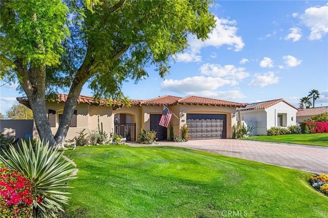 mediterranean / spanish home featuring decorative driveway, stucco siding, an attached garage, a front yard, and a tiled roof