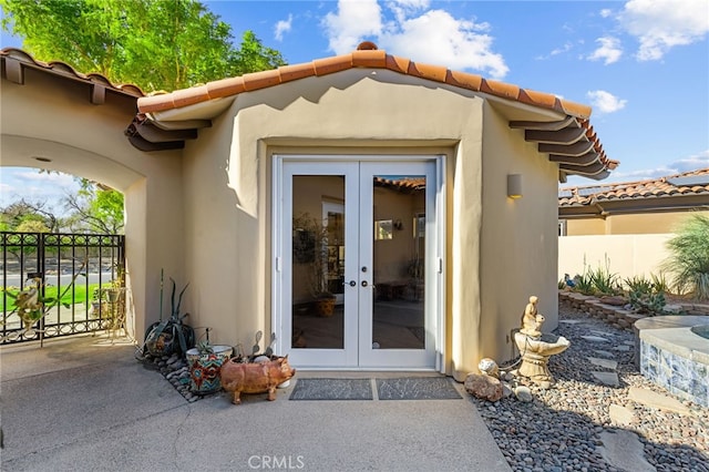 doorway to property with french doors, fence, and stucco siding