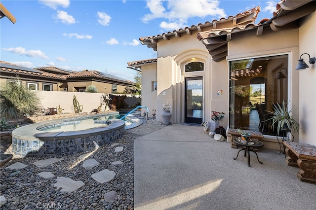 view of patio featuring a pool with connected hot tub and fence