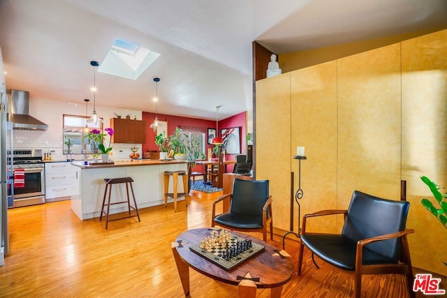 sitting room with light hardwood / wood-style floors and vaulted ceiling with skylight