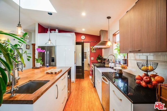 kitchen featuring sink, appliances with stainless steel finishes, hanging light fixtures, island range hood, and wood counters