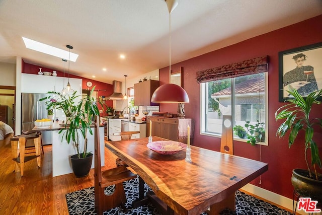 dining room with hardwood / wood-style floors and vaulted ceiling with skylight