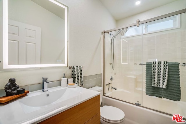 full bathroom featuring vanity, shower / bath combination with glass door, and toilet