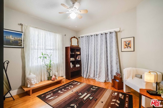 living area featuring hardwood / wood-style flooring, ceiling fan, and lofted ceiling