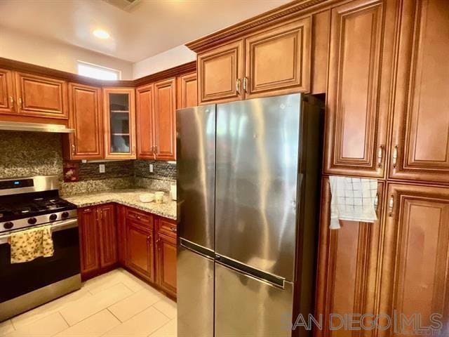 kitchen with tasteful backsplash, light stone countertops, and appliances with stainless steel finishes