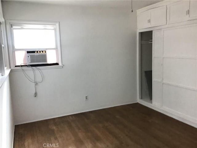 unfurnished bedroom featuring a closet, cooling unit, and dark wood-type flooring