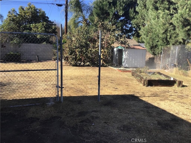 view of yard featuring a vegetable garden, fence, an outdoor structure, and a shed