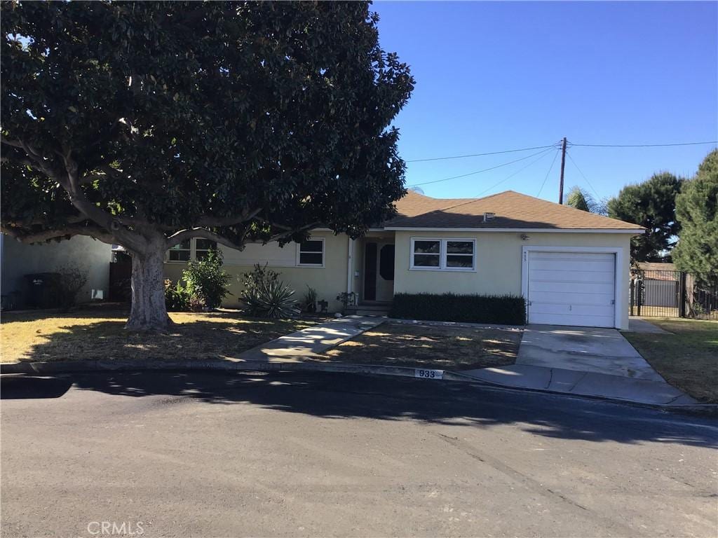 view of front of property with an attached garage, fence, concrete driveway, and stucco siding