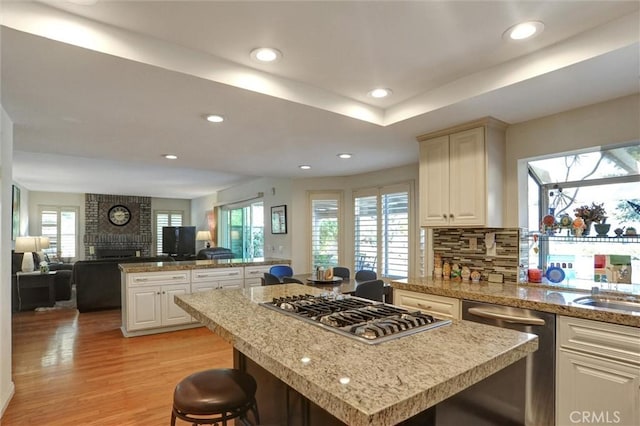 kitchen featuring appliances with stainless steel finishes, a kitchen breakfast bar, decorative backsplash, a center island, and light hardwood / wood-style flooring