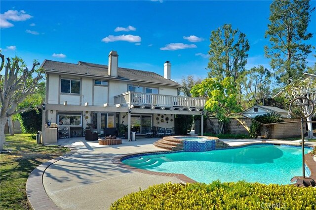 rear view of property featuring a balcony, a pool with hot tub, and a patio area