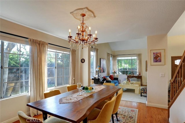 dining area featuring an inviting chandelier, light hardwood / wood-style flooring, and vaulted ceiling