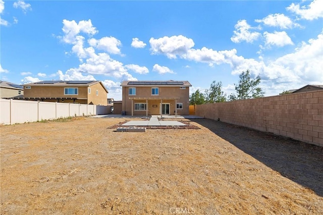 back of property featuring a patio area and solar panels