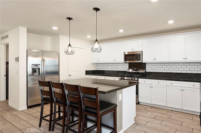 kitchen featuring appliances with stainless steel finishes, a center island, white cabinets, and decorative light fixtures