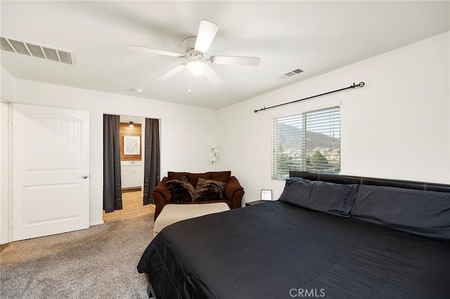 bedroom featuring ensuite bathroom, light carpet, and ceiling fan