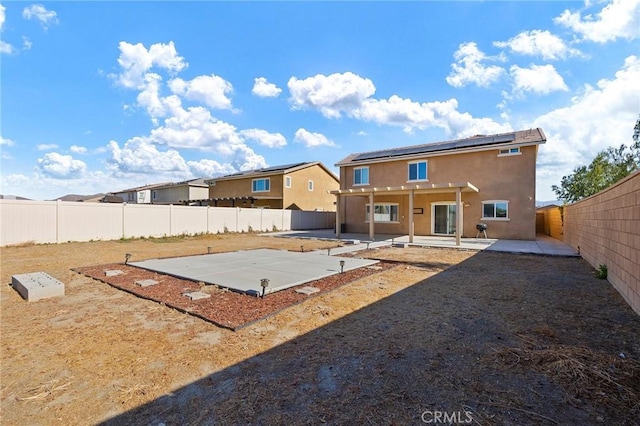 rear view of property with a patio area and solar panels