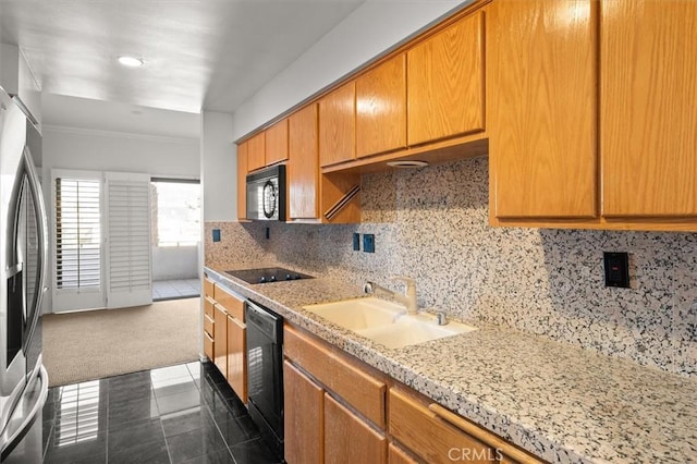 kitchen featuring sink, dark tile patterned flooring, light stone countertops, decorative backsplash, and black appliances