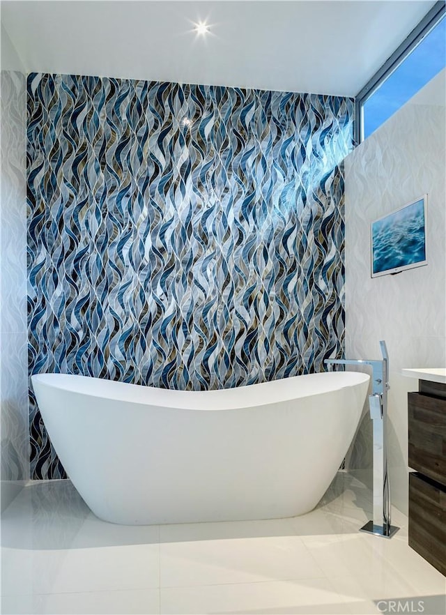 bathroom with vanity, tile walls, and a tub to relax in