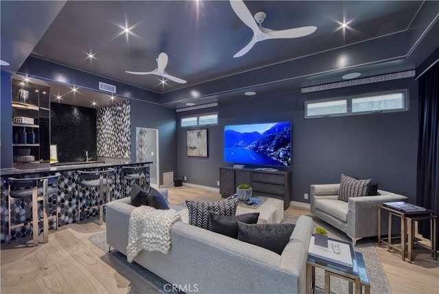 home theater room featuring wood-type flooring, ceiling fan, and indoor bar