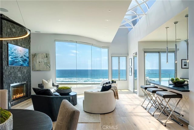 living room with a water view, lofted ceiling, a fireplace, and light hardwood / wood-style floors