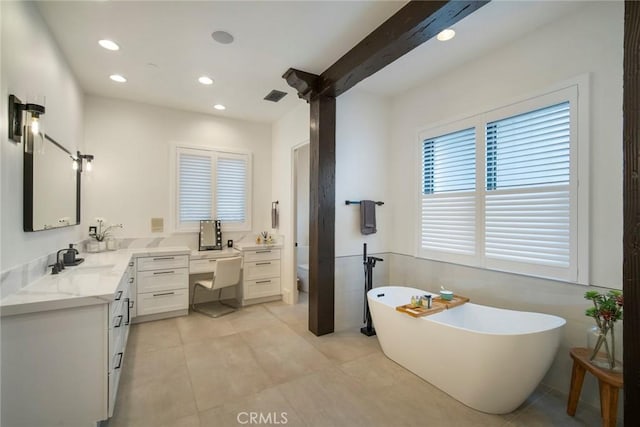 bathroom featuring tile patterned flooring, beam ceiling, vanity, a tub to relax in, and toilet