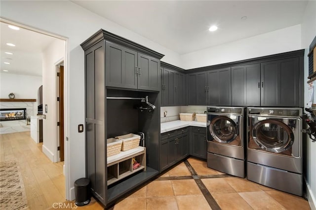 laundry area featuring a high end fireplace, cabinets, and washing machine and clothes dryer